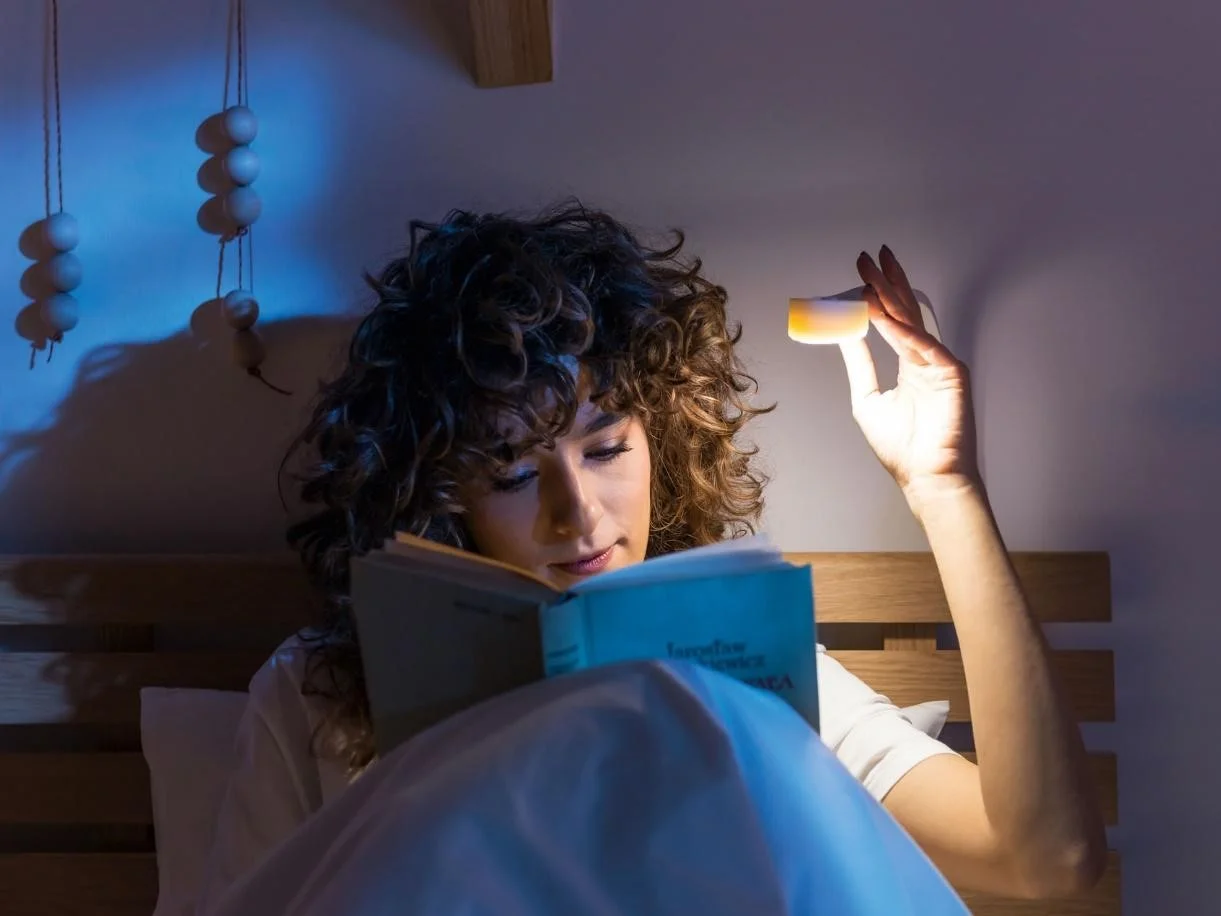 kobieta czyta książce przy lampce LED